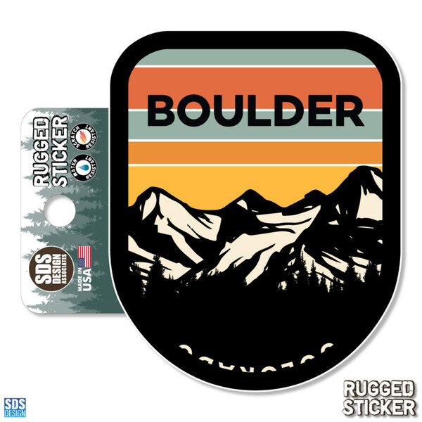 Rugged sticker featuring a silhouette of Colorado mountains and pine trees beneath a retro sunset sky with the word “BOULDER” in bold black letters.